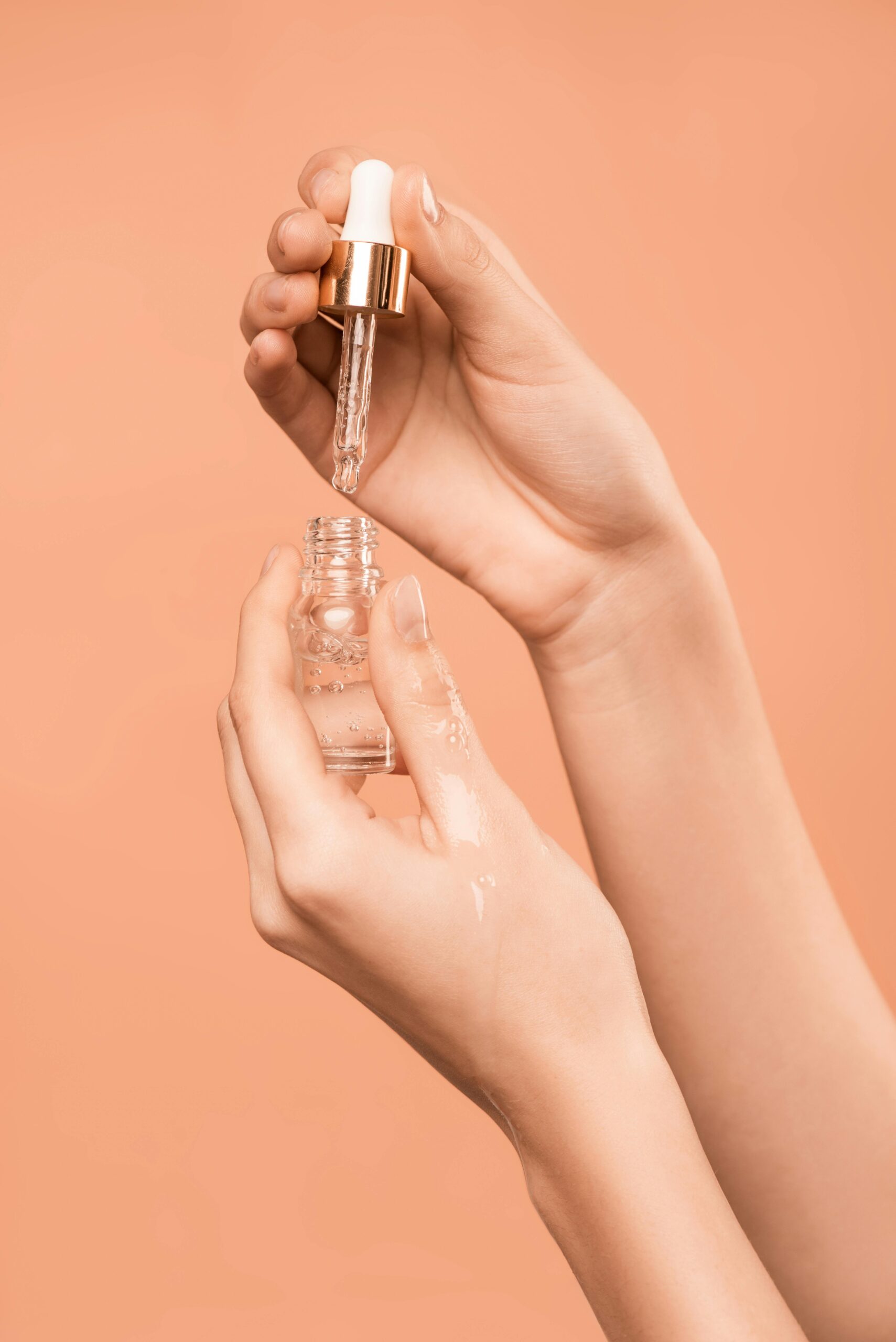 pexels-photo-3762882-3762882 Close-up of hands using a dropper to apply skincare serum, ideal for health and beauty content.